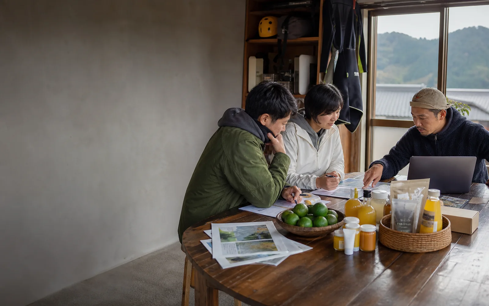 じゃばら商品と体験予約、交通案内を前に、北山村の事業者と遠方への伝え方を相談する様子