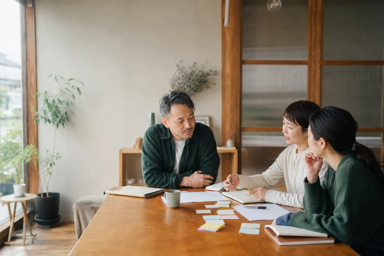 担当者が経営者の話を聞き、ホームページに載せる内容をメモしている場面