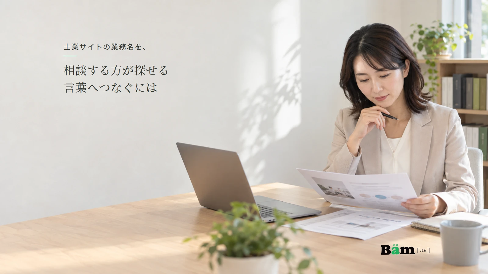 専門事務所の担当者が、業務案内の資料とノートパソコンを見ながら掲載する説明を検討する様子。