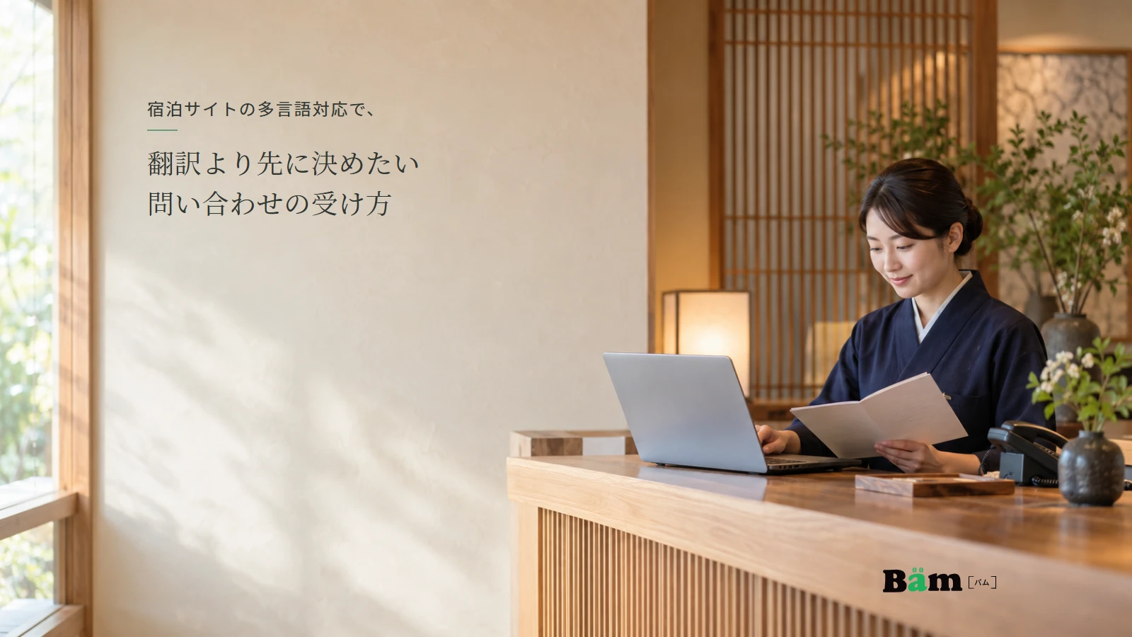 小規模な宿の受付担当者がパソコンと館内案内を確認する説明用イメージ。実在の宿泊施設の接客記録ではない。