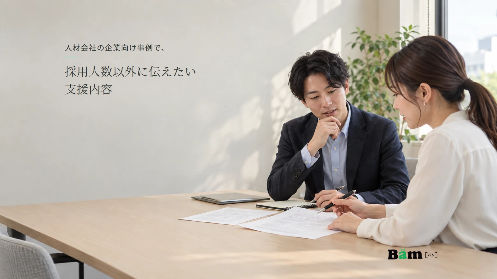 人材会社の担当者と企業の採用担当者が、募集条件の資料を見ながら打ち合わせる様子。