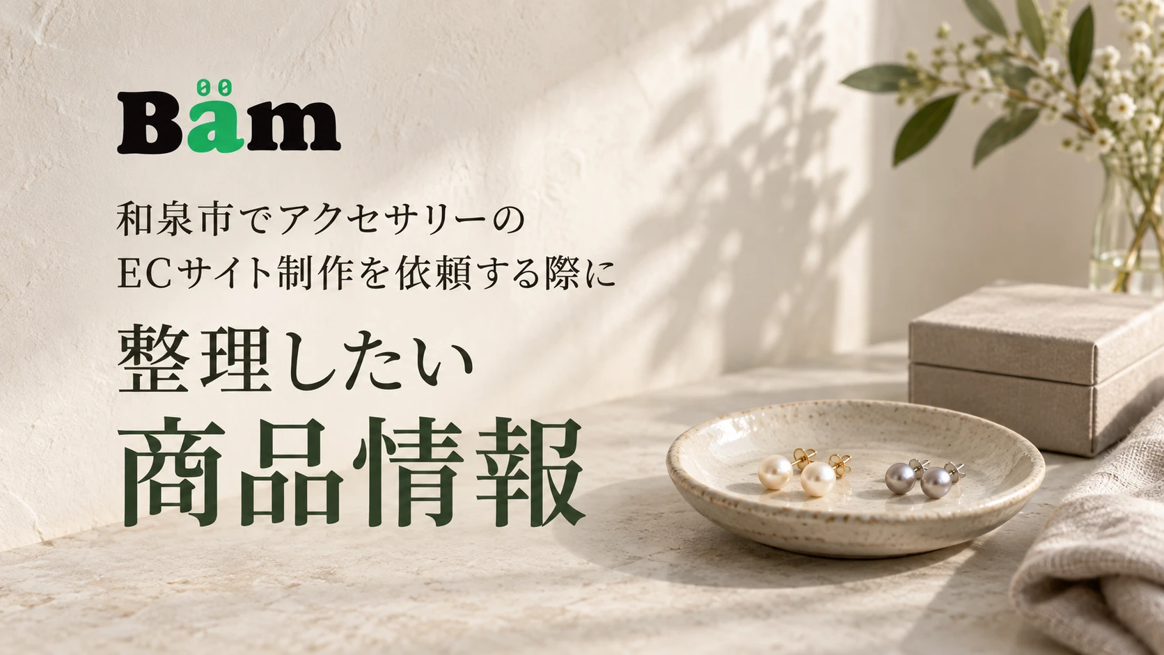 和泉市でアクセサリーのECサイト制作を依頼する際に整理したい商品情報というタイトルとBämロゴを、パールのピアスと小箱のある落ち着いたテーブルに配したメインビジュアル