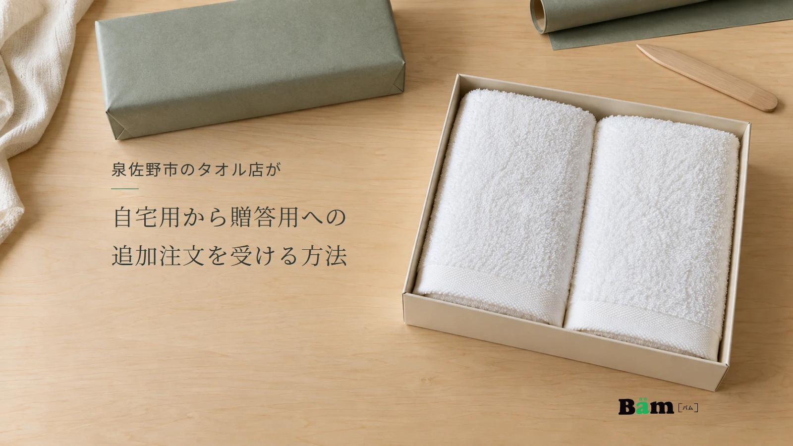 泉佐野市のタオル店が自宅用から贈答用への追加注文を受ける方法というタイトル、二枚の白タオルを入れた箱と包装済みの箱がある作業台、右下にBämロゴ