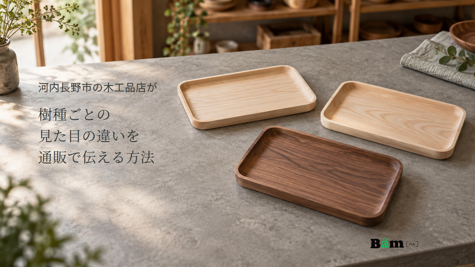 河内長野市の木工品店が樹種ごとの見た目の違いを通販で伝える方法というタイトル、木工品店の展示卓に並ぶ淡い木色と濃い茶色の小物トレー、右下にBämロゴ