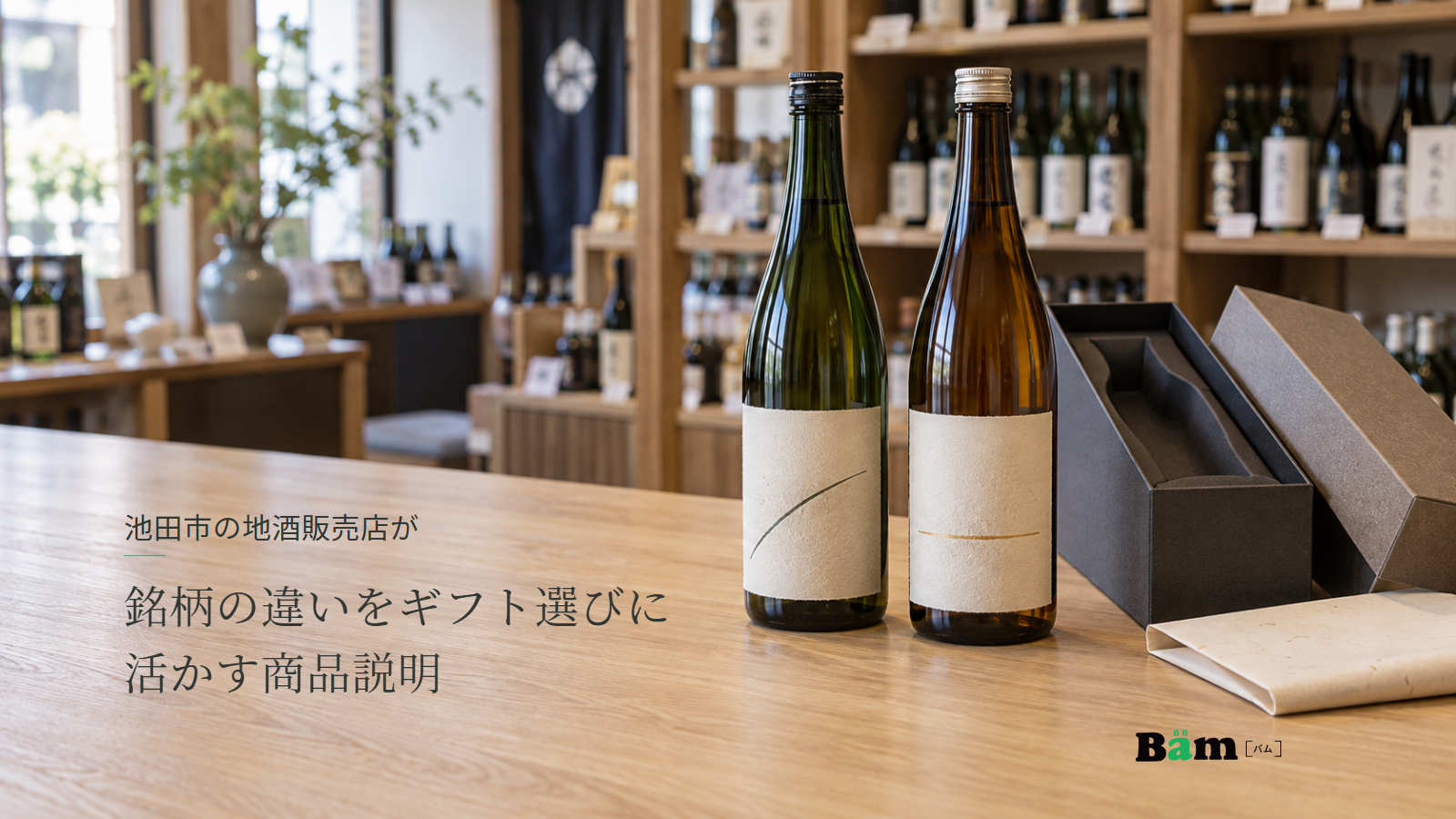 池田市の地酒販売店が銘柄の違いをギフト選びに活かす商品説明というタイトル、酒販店の木のカウンターに並ぶ二本の日本酒と一本用の贈答箱、右下のBämロゴ