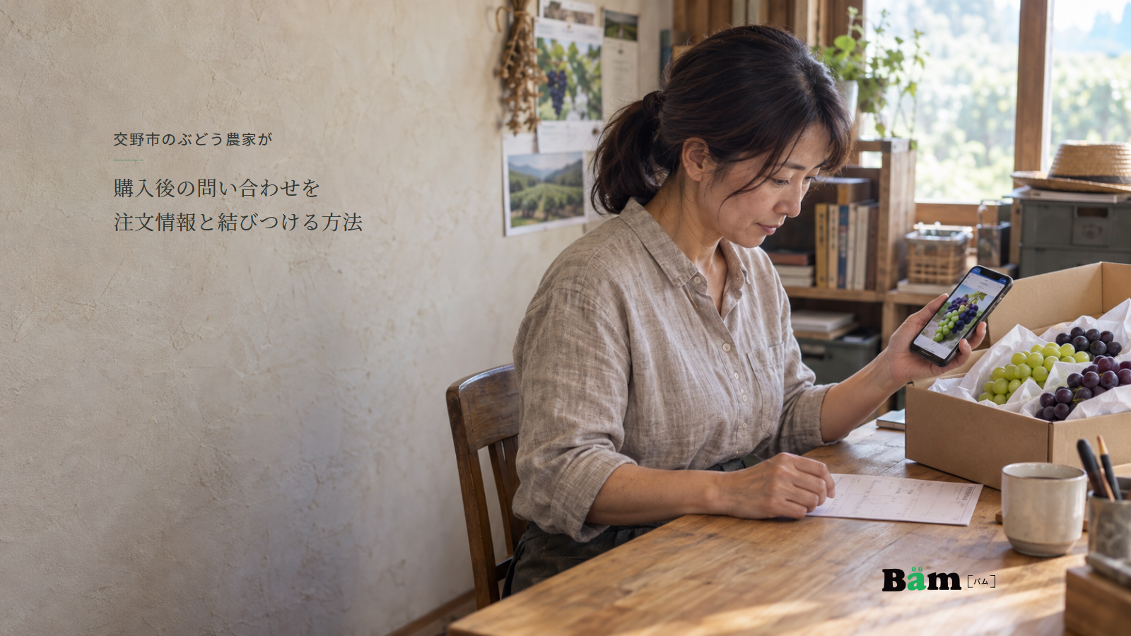 ぶどう農園の机でスマートフォンのぶどう写真と注文控えを確認する女性、箱入りのぶどう、交野市のぶどう農家が購入後の問い合わせを注文情報と結びつける方法の全文タイトル、右下のBämロゴ
