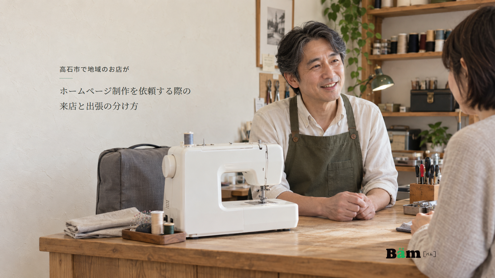 ミシンと持ち運びケース、布や整備道具のある店で店主が相談を受ける場面、高石市で地域のお店がホームページ制作を依頼する際の来店と出張の分け方の全文タイトル、右下のBämロゴ