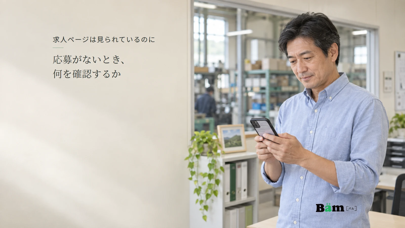 小さな工場の事務所でスマートフォンの求人ページを確認する採用担当者の説明用写真。全文タイトルと正式Bämロゴを配置。