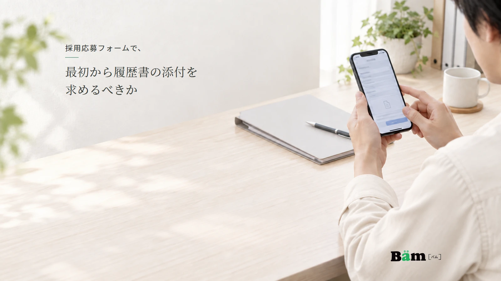 応募書類の入ったフォルダーを机に置き、スマートフォンで応募画面を確認する説明用イメージ写真。実在の応募者や個人情報ではない。全文タイトルと正式Bämロゴを配置。