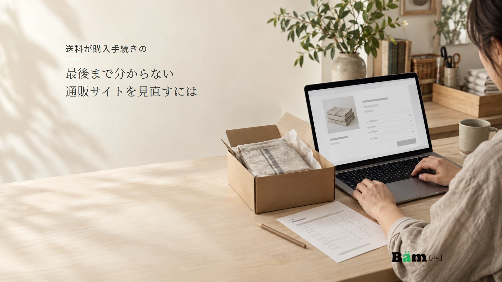 キッチンクロスの梱包と通販の送料案内を机上で確認する場面。全文タイトルと正式Bämロゴを配置。