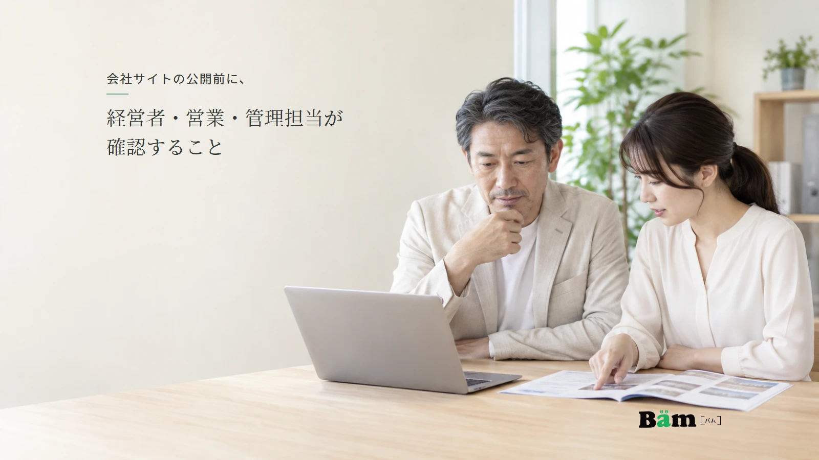 会社の担当者が公開前のサイト画面と会社案内を見比べて、掲載内容を確認する様子。
