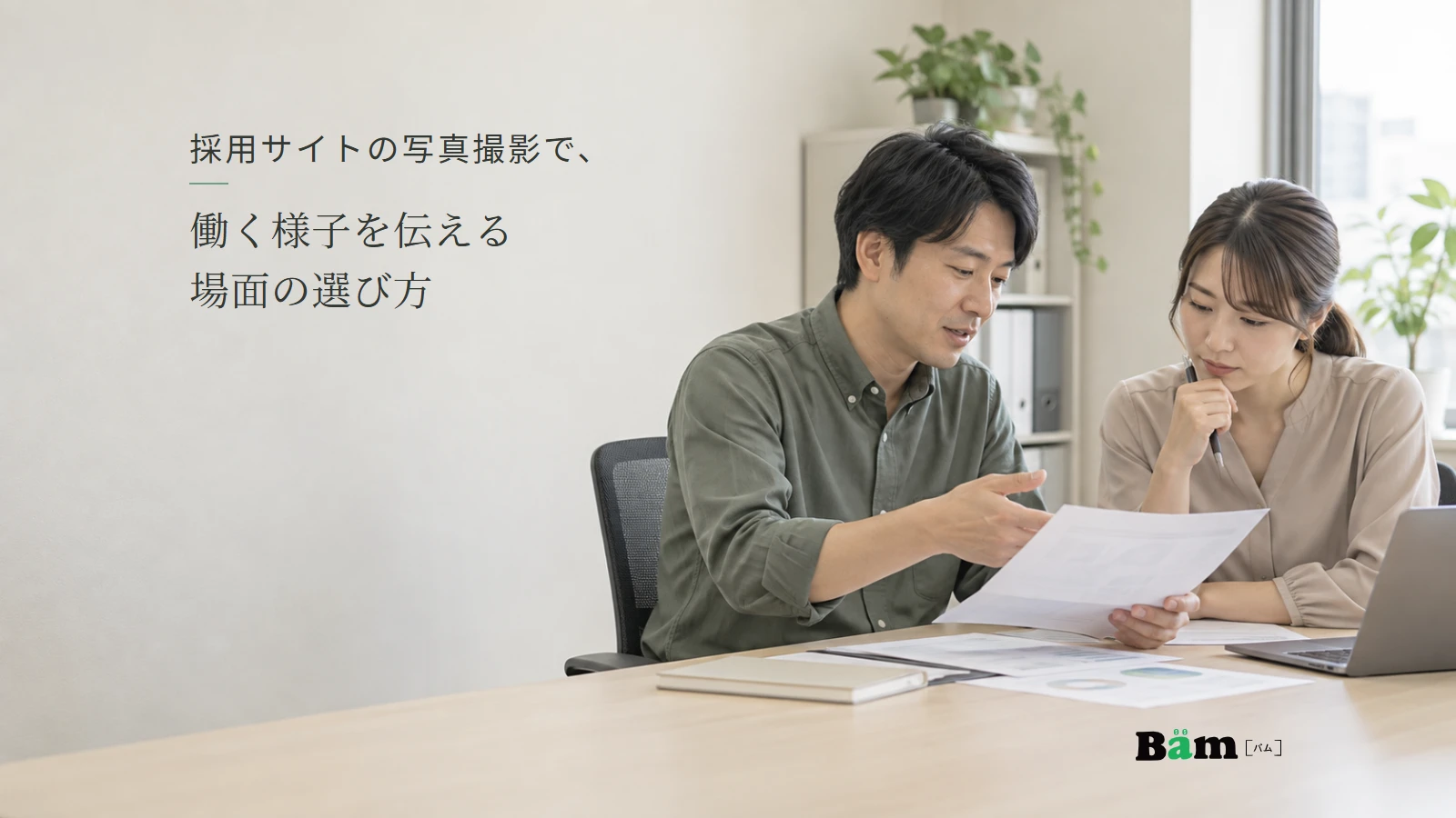 同僚と資料を確認する仕事場面のイメージ。記事の全文タイトルと正式Bämロゴ。